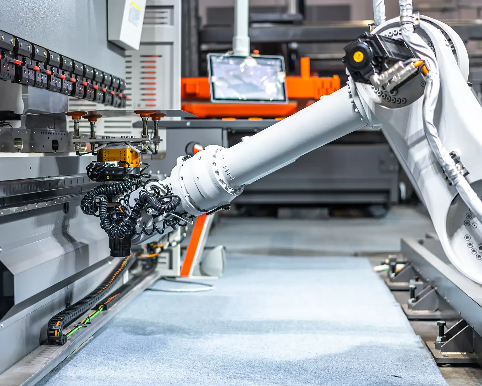 Industriell robotarm i produksjonsmiljø som opererer ved en maskin.